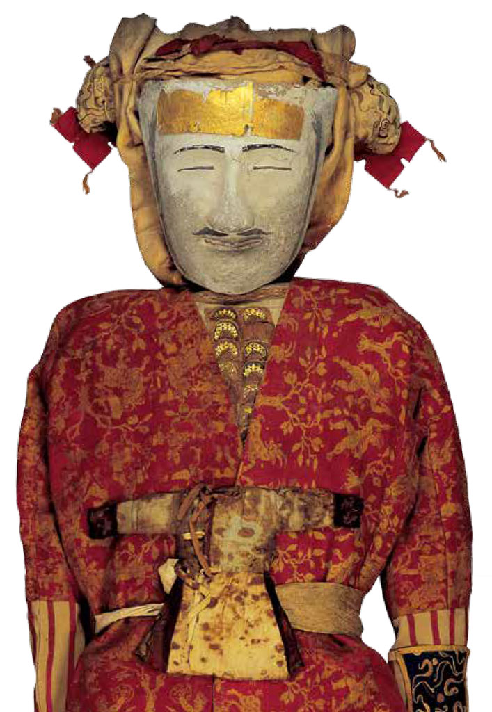 A mummy wearing a mask and red and gold garments.