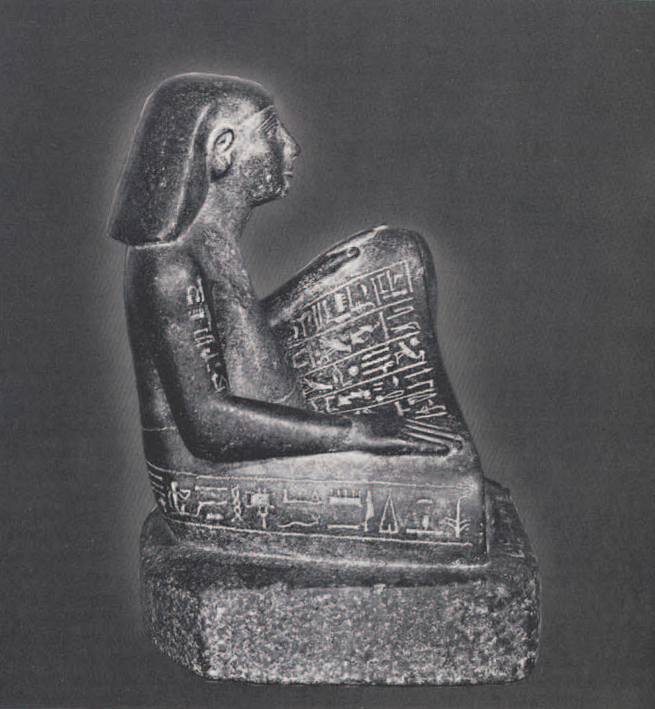 Seated statue of a scribe wearing a short kilt and a short wig. The lap, sides and base of the statue are inscribed with a text.