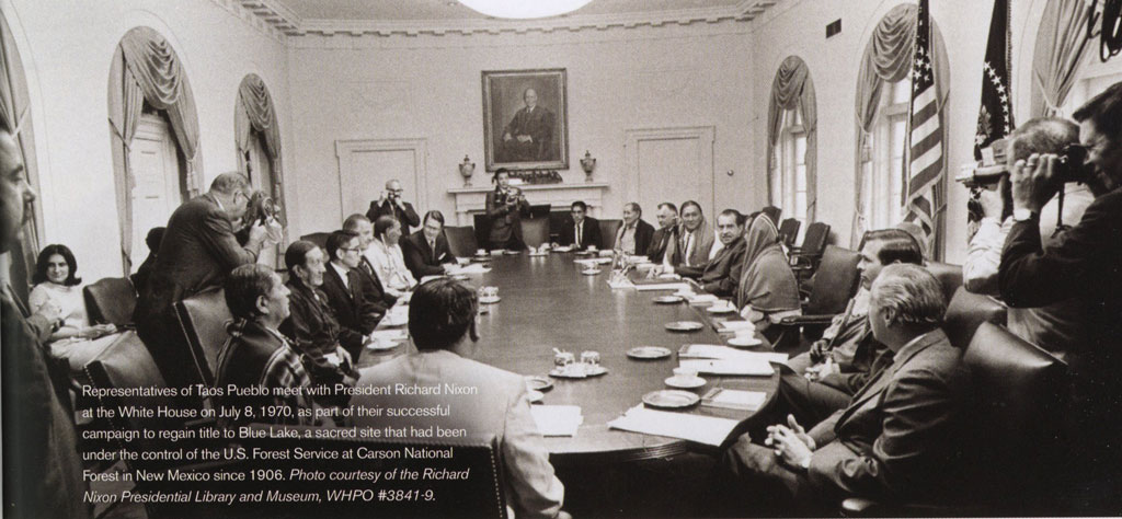 A group of representatives seated around a table in the White House with the president.