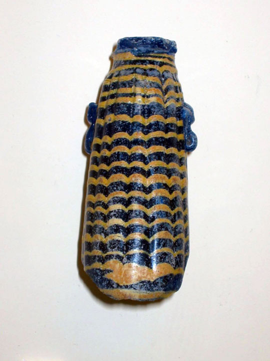 A small blue and yellow striped coreform vessel.