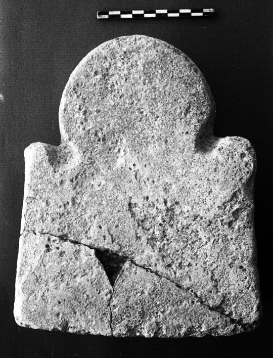 A small stone carving with a rectangular base and 3/4 circle atop.