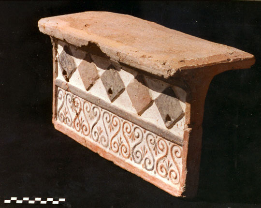 A terracotta tile with a diamond and swirl decorative motif.