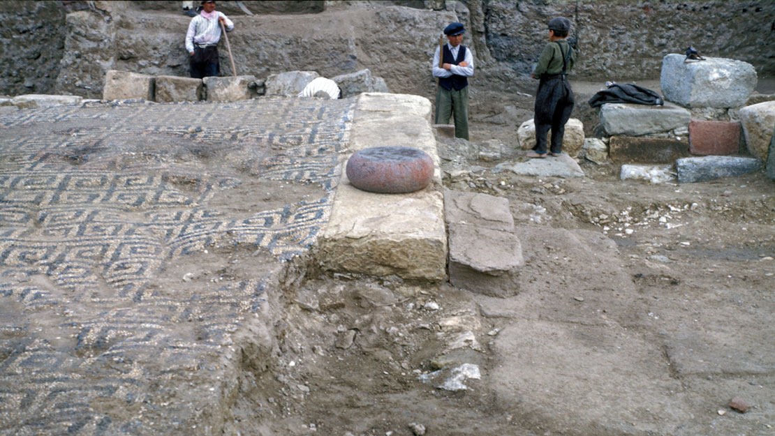 An excavated floor covered in geometric mosaic in the meander pattern.