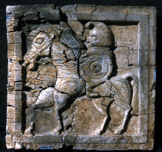 A cracked square tile of a solider on a horse.