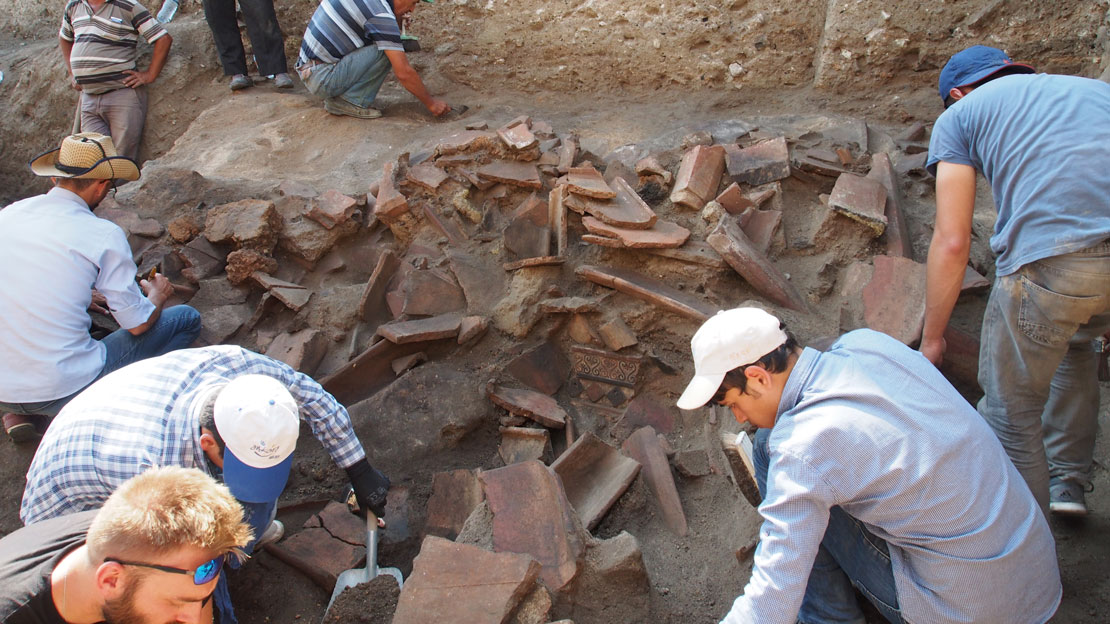 People excavating a jumble of architectural terracottas in situ.