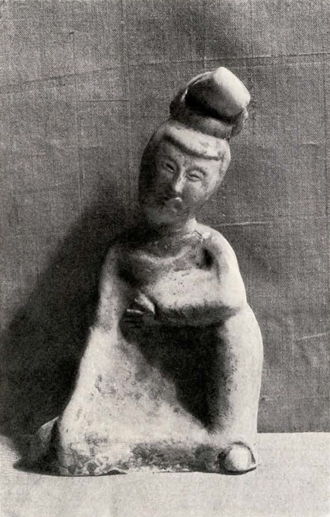 a figurine of a seated woman with her hand at her heart