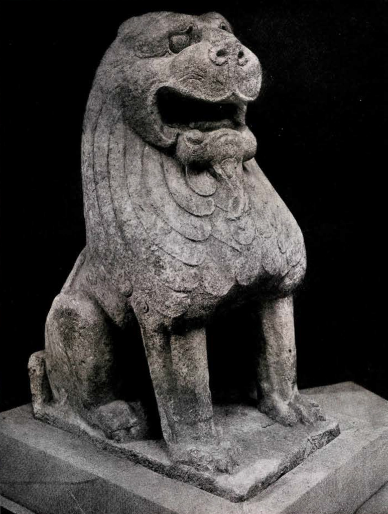 A seated stone lion with its mouth open and with a beard and mane in low relief