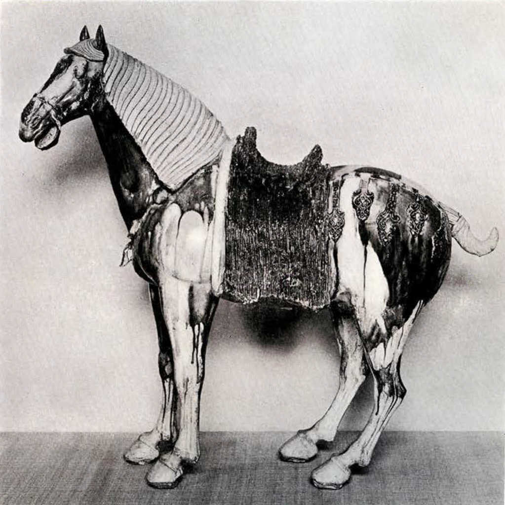 Pottery figurine of a standing horse wearing a saddle with its mouth open