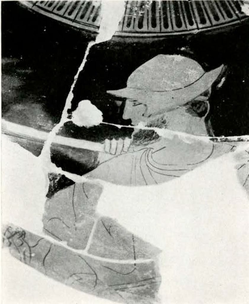 Close up of fragmented area from loutrophoros, showing the head and torso of a man wearing a hat or helmet, pieces missing