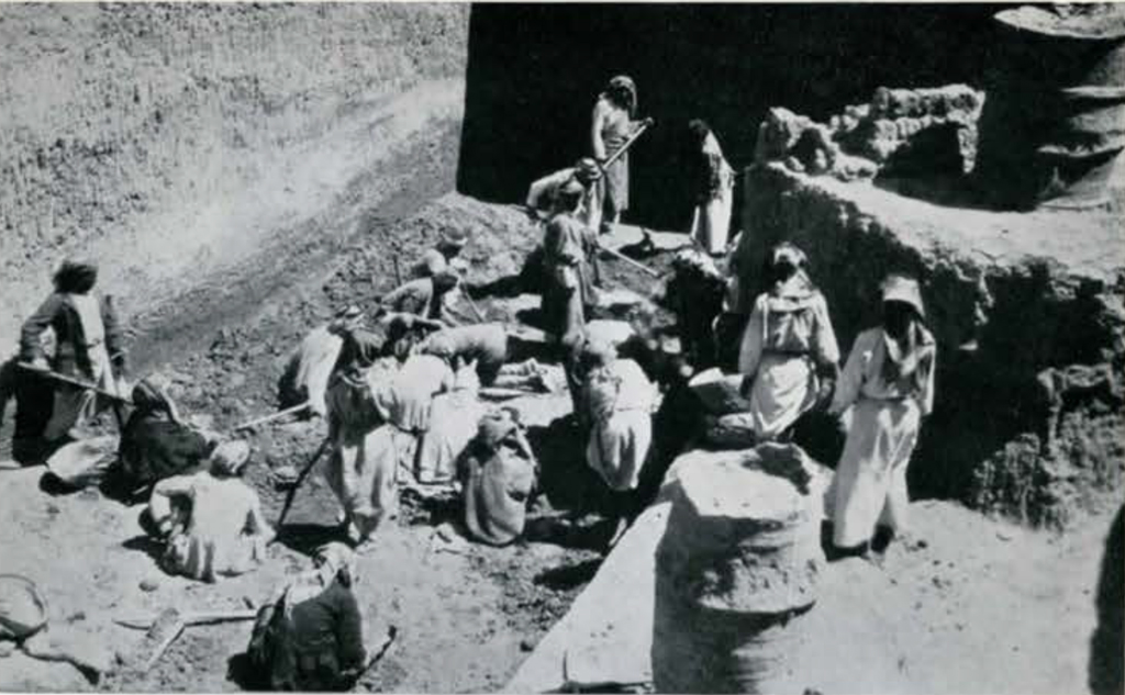 A group of men excavating in a square pit