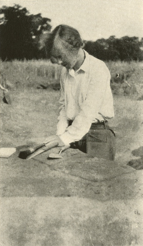 A person holding their tools, waist deep in a pit
