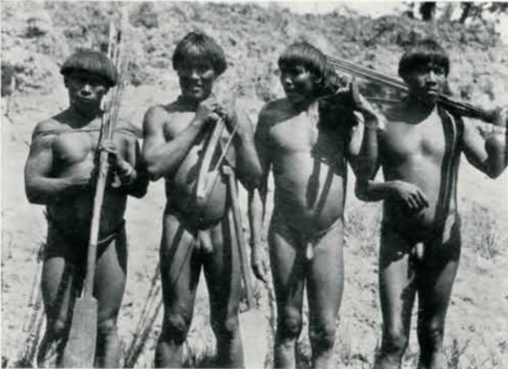 Four men standing together, holding spears or arrows or paddles