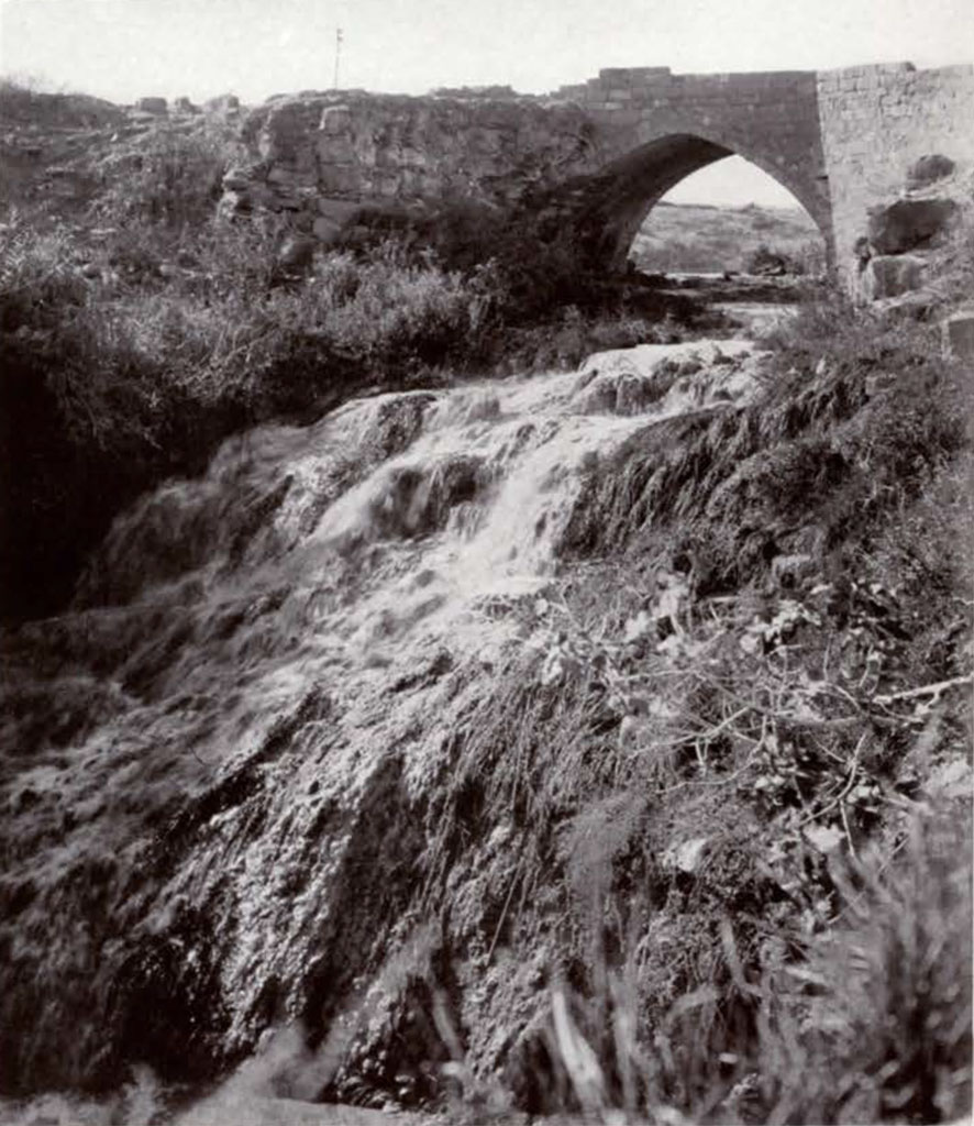 A brick arched bridge over a waterfall